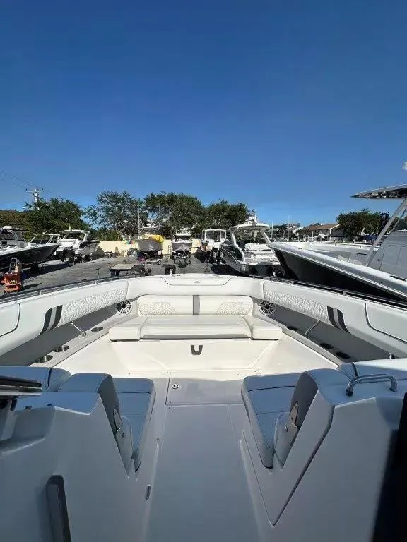 Slide: The Image of 2023 Regal LX36 boat interior with seating, docked under clear blue sky. - 7