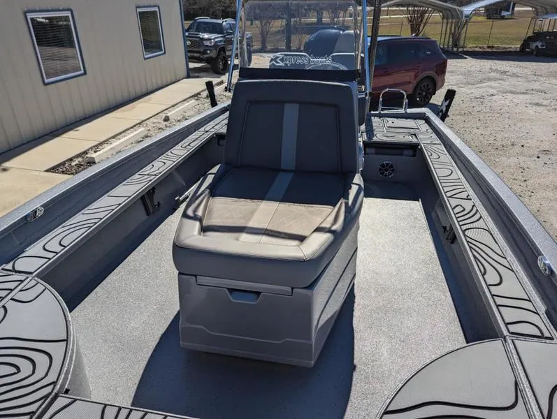 Slide: The Image of 2025 Xpress X23B Lounge boat interior with seating and storage, parked outdoors. - 19
