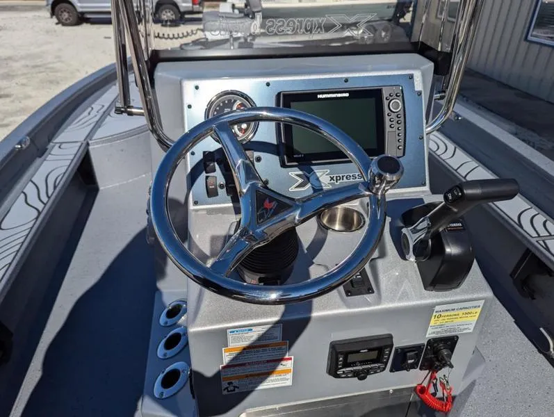 Slide: The Image of 2025 Xpress X23B Lounge boat dashboard with steering wheel and navigation controls. - 7