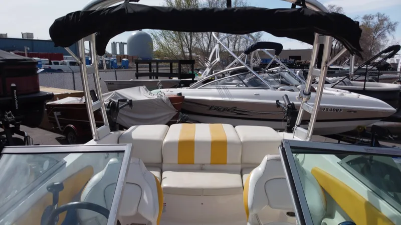 Slide: The Image of 2012 Chaparral 19 Ski & Fish H2O boat with yellow-striped seating, docked among other boats. - 8