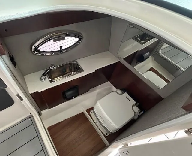 Slide: The Image of 2023 Chaparral 267 SSX boat interior with sink, mirror, and compact toilet. - 7