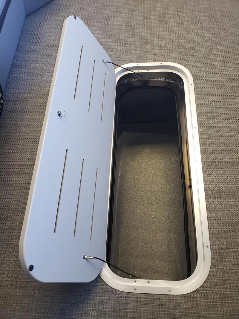 Slide: The Image of 2025 Bentley Pontoons Elite Admiral storage compartment with open lid on textured surface. - 14