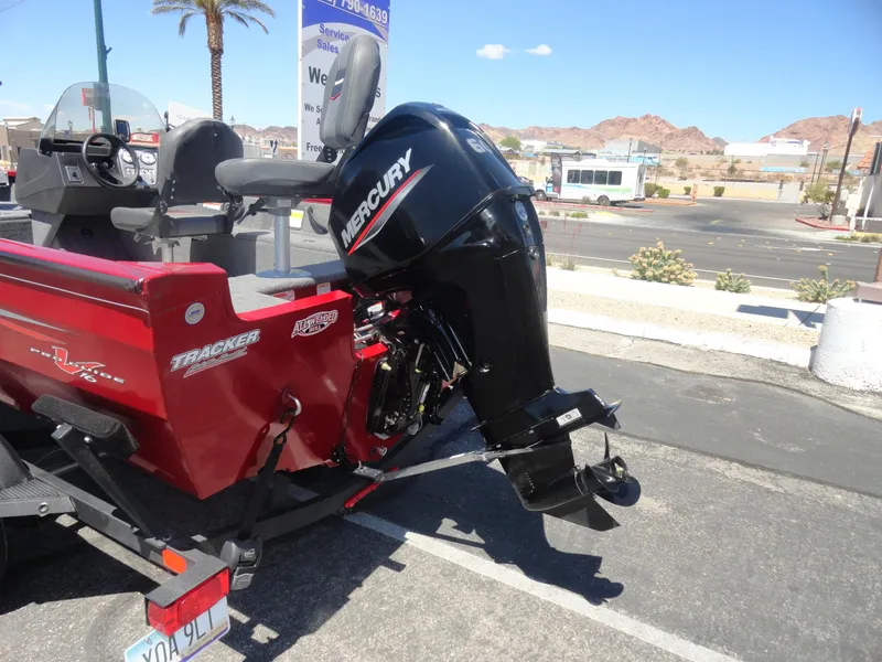 Slide: The Image of 2024 Tracker Pro Guide V-16 SC boat with Mercury outboard motor in a parking lot. - 20