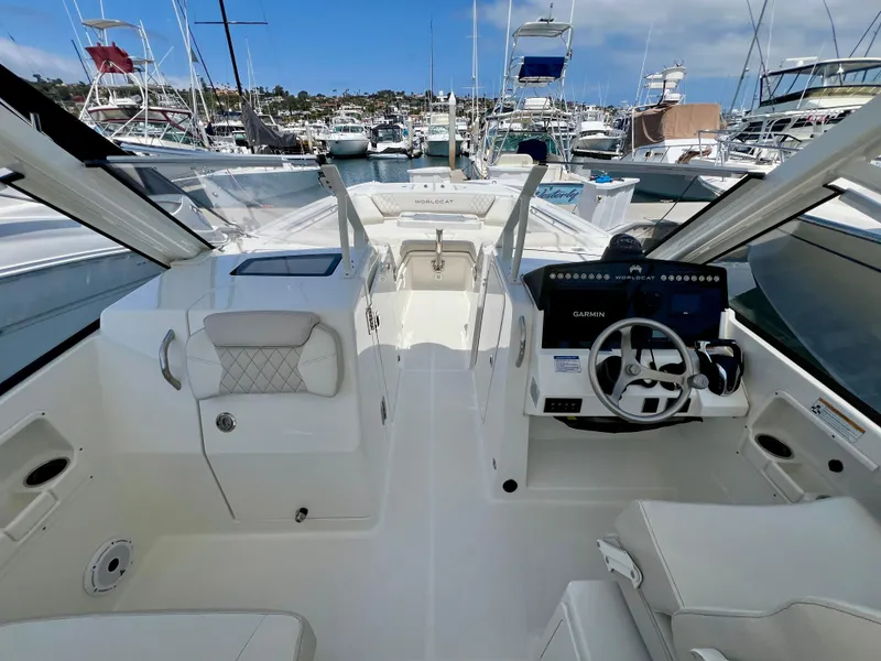 Slide: The Image of 2024 World Cat 280DC-x boat interior with helm, seating, and marina view. - 10