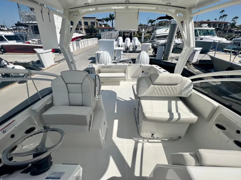 Slide: The Image of 2024 World Cat 280DC-x boat interior with white seating and steering wheel at marina. - 11