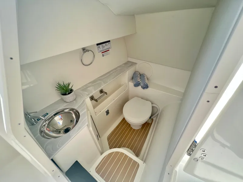 Slide: The Image of 2024 World Cat 280DC-x boat bathroom with sink, toilet, and wooden floor accents. - 13