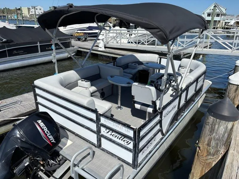 Slide: The Image of 2020 Bentley Pontoons LE 180 Cruise at dock, featuring a Mercury outboard motor. - 2