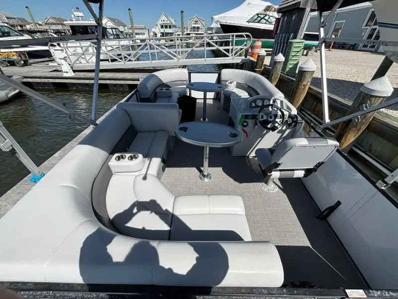 Slide: The Image of 2020 Bentley Pontoons LE 180 Cruise interior with seating and steering wheel at a marina. - 4