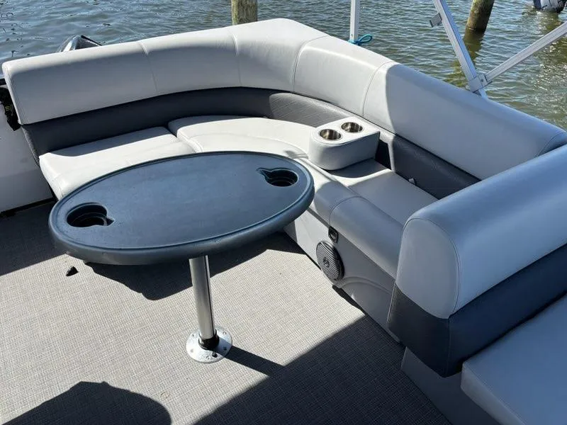 Slide: The Image of 2020 Bentley Pontoons LE 180 Cruise interior with gray seating and round table on water. - 6