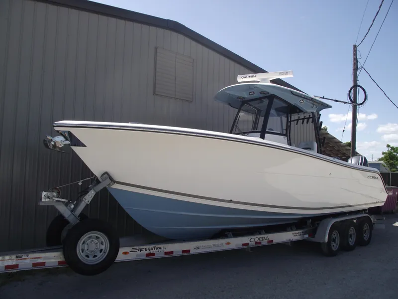 Slide: The Image of 2021 Cobia 301 Center Console boat on trailer, parked beside a building. - 1