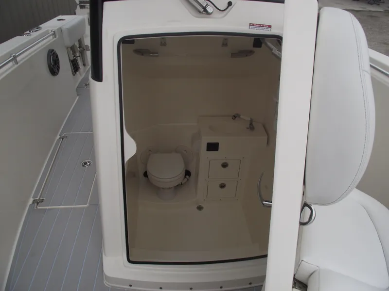 Slide: The Image of 2021 Cobia 301 Center Console boat interior with compact bathroom and sink. - 19