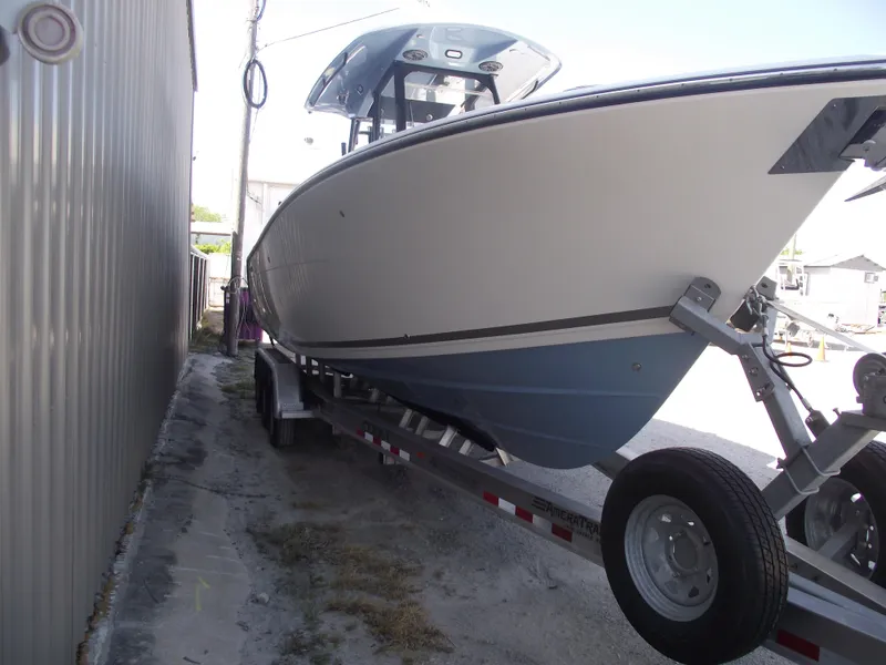 Slide: The Image of 2021 Cobia 301 Center Console boat on trailer, parked beside a building. - 2