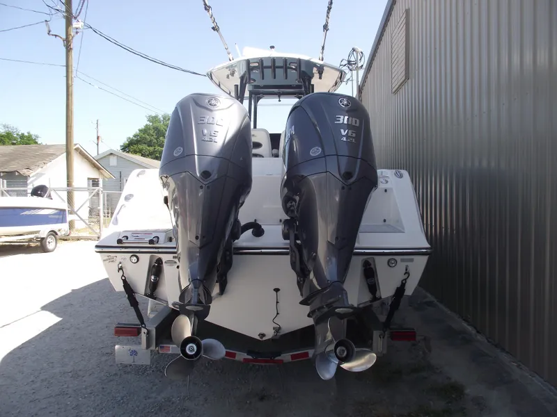 Slide: The Image of 2021 Cobia 301 Center Console boat with dual outboard engines, parked near a building. - 3