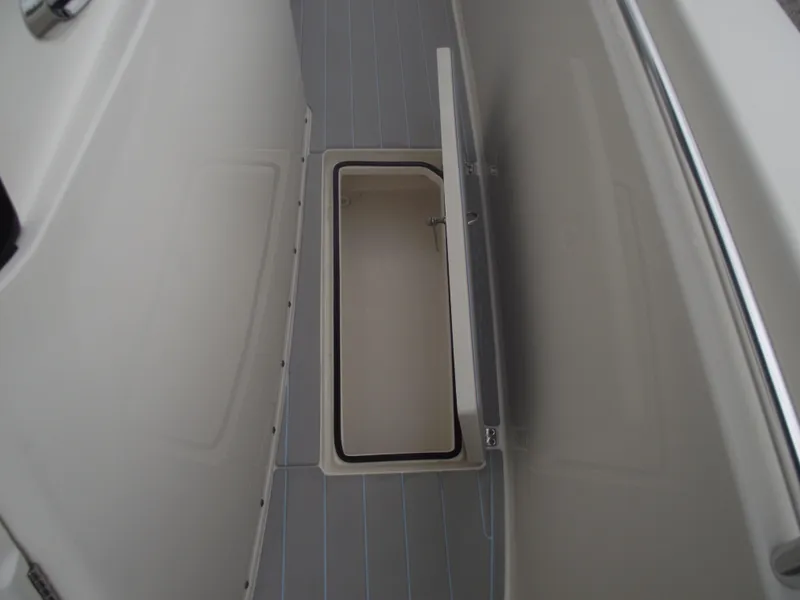 Slide: The Image of 2021 Cobia 301 Center Console boat storage compartment with open lid. - 30