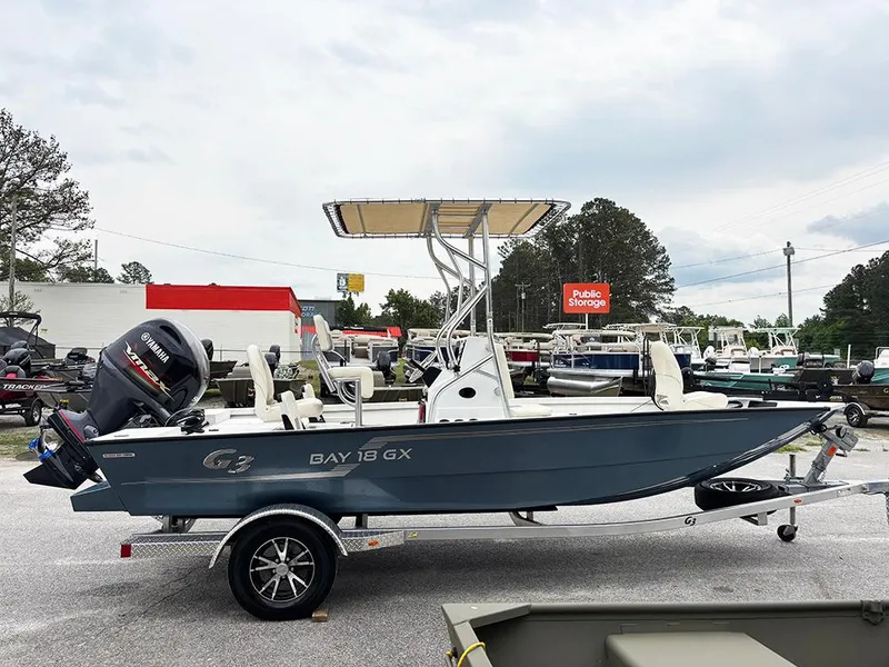 Slide: The Image of 2023 G3 Bay 18 GX boat on trailer, parked outdoors, with Yamaha outboard motor. - 6