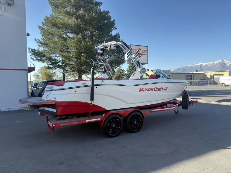Slide: The Image of 2018 MasterCraft XT23 boat with red and white design on a trailer, parked outdoors. - 4