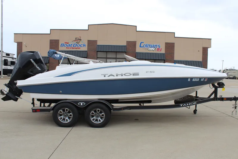 Slide: The Image of 2022 Tahoe 2150 boat on trailer, parked outside dealership, featuring sleek design and modern outboard motor. - 0