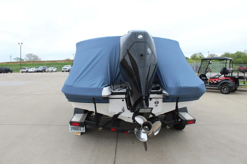 Slide: The Image of 2022 Tahoe 2150 boat with blue cover and outboard motor, parked on concrete. - 14