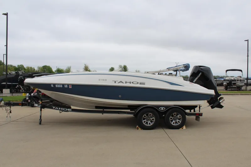 Slide: The Image of 2022 Tahoe 2150 boat on trailer, parked outdoors on a cloudy day. - 4