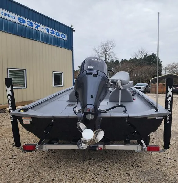 Slide: The Image of 2024 Xpress XP200 Catfish boat with outboard motor, parked outside a building. - 2