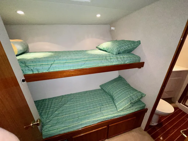 Slide: The Image of Bunk beds with green striped bedding in a 1997 Post 50 Convertible yacht cabin. - 24