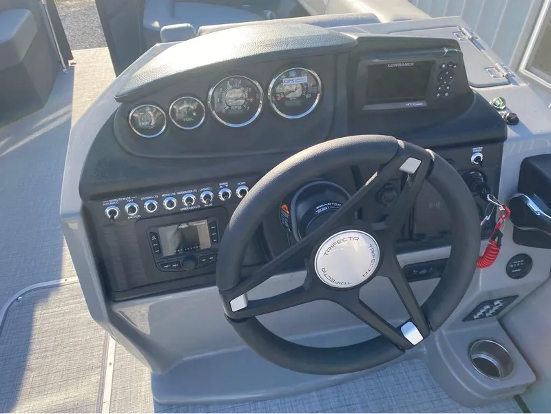 Slide: The Image of 2025 Trifecta C Series 24RFC boat dashboard with steering wheel and control panel. - 13