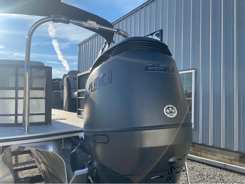 Slide: The Image of 2025 Trifecta C Series 24RFC pontoon boat with Suzuki outboard motor, docked outdoors. - 6