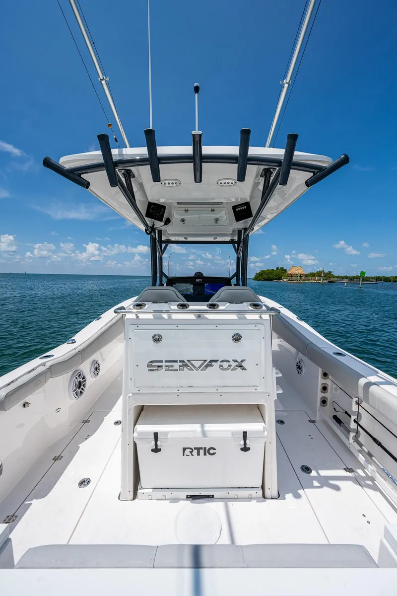 Slide: The Image of 2022 Sea Fox 288 Commander boat on water, featuring spacious deck and fishing rod holders. - 27