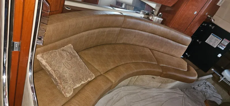 Slide: The Image of 2005 Sea Ray 360 Sundancer interior with curved leather seating and wooden cabinetry. - 12