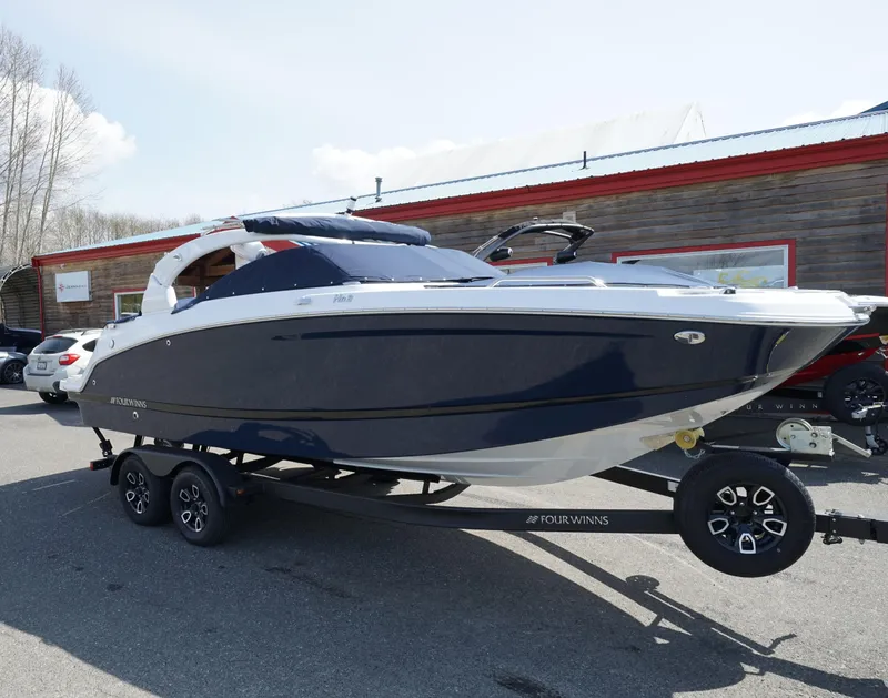 Slide: The Image of 2023 Four Winns HD3 Surf boat on trailer, parked outdoors. - 0