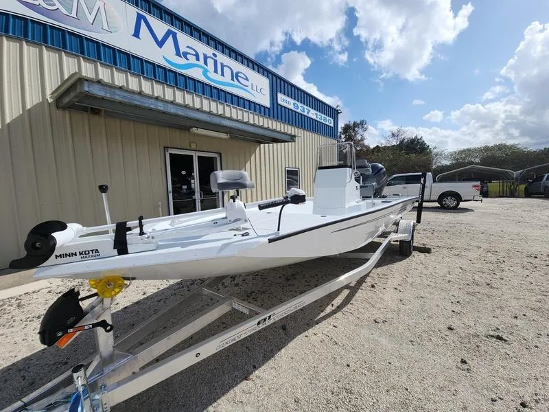 Slide: The Image of 2025 Xpress H210 BAY boat on trailer outside marine dealership under blue sky. - 1