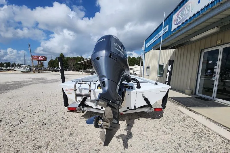Slide: The Image of 2025 Xpress H210 BAY boat with outboard motor, parked outside a dealership under a cloudy sky. - 14