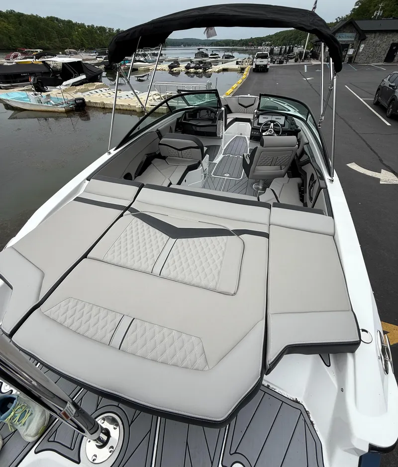 Slide: The Image of 2025 Monterey 235 Super Sport boat with sleek seating at a lakeside dock. - 5