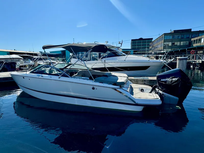 Slide: The Image of 2023 Four Winns H2 boat docked in marina, featuring sleek design and Mercury outboard engine. - 2