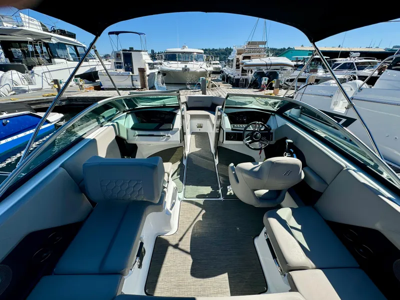 Slide: The Image of 2023 Four Winns H2 boat interior with seating and steering wheel at a marina. - 10