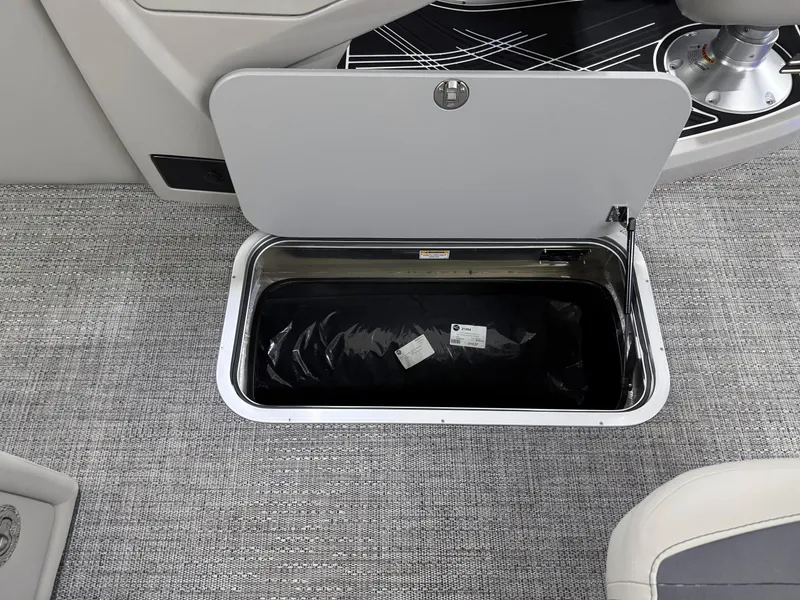 Slide: The Image of 2025 Barletta Corsa 23UC boat storage compartment with open lid on gray carpet. - 24