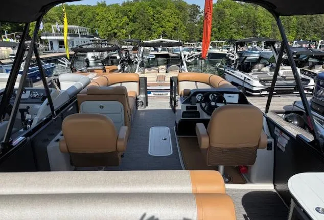 Slide: The Image of 2025 Crest Classic 220 pontoon boat interior at marina, featuring tan seating and modern dashboard. - 7
