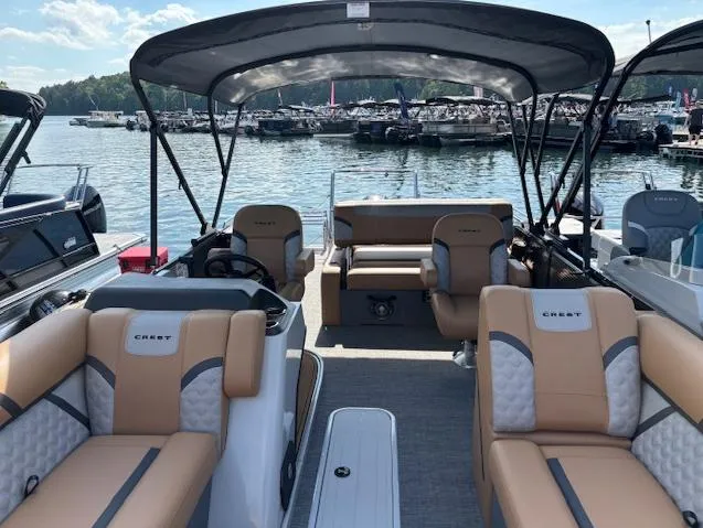 Slide: The Image of 2025 Crest Classic 220 pontoon boat with tan seating, canopy, and lake backdrop. - 8