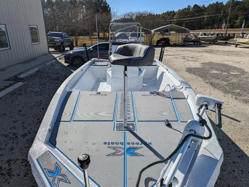 Slide: The Image of 2025 Xpress H210B boat with seating and fishing equipment, parked outdoors. - 11