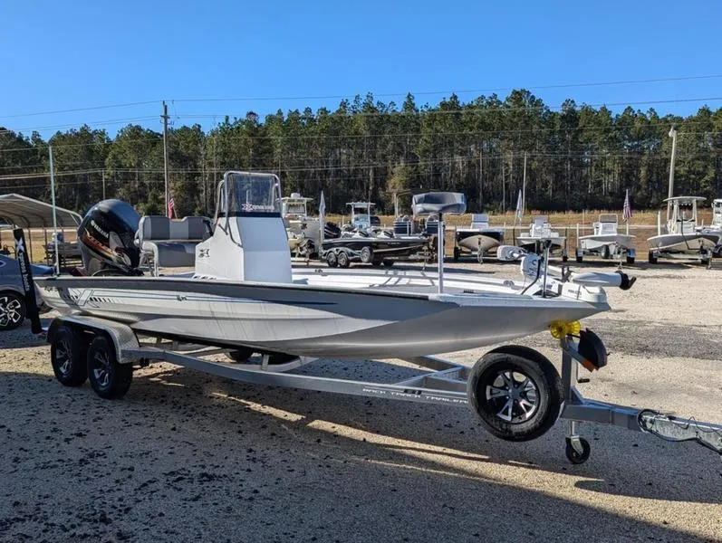 Slide: The Image of 2025 Xpress H210B boat on trailer, parked outdoors with trees in background. - 2