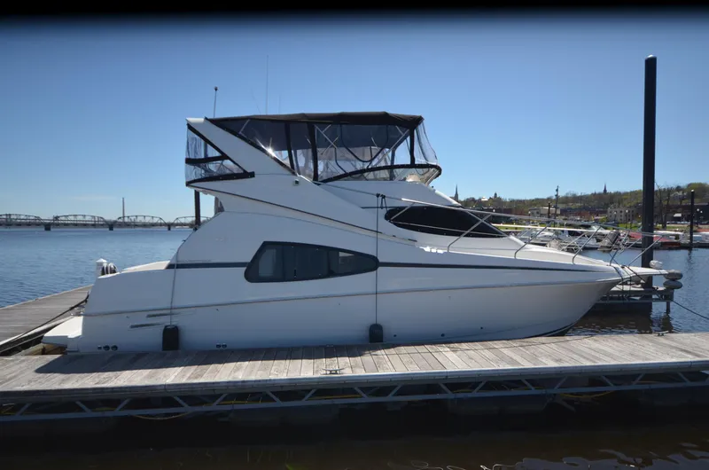 The Image of 2000 Silverton 330 Sport Bridge yacht docked at a marina under clear blue skies. - 1