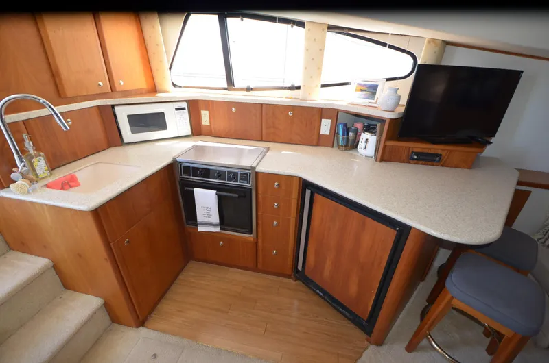 Slide: The Image of 2000 Silverton 330 Sport Bridge kitchen with wood cabinetry, microwave, stove, and TV. - 15