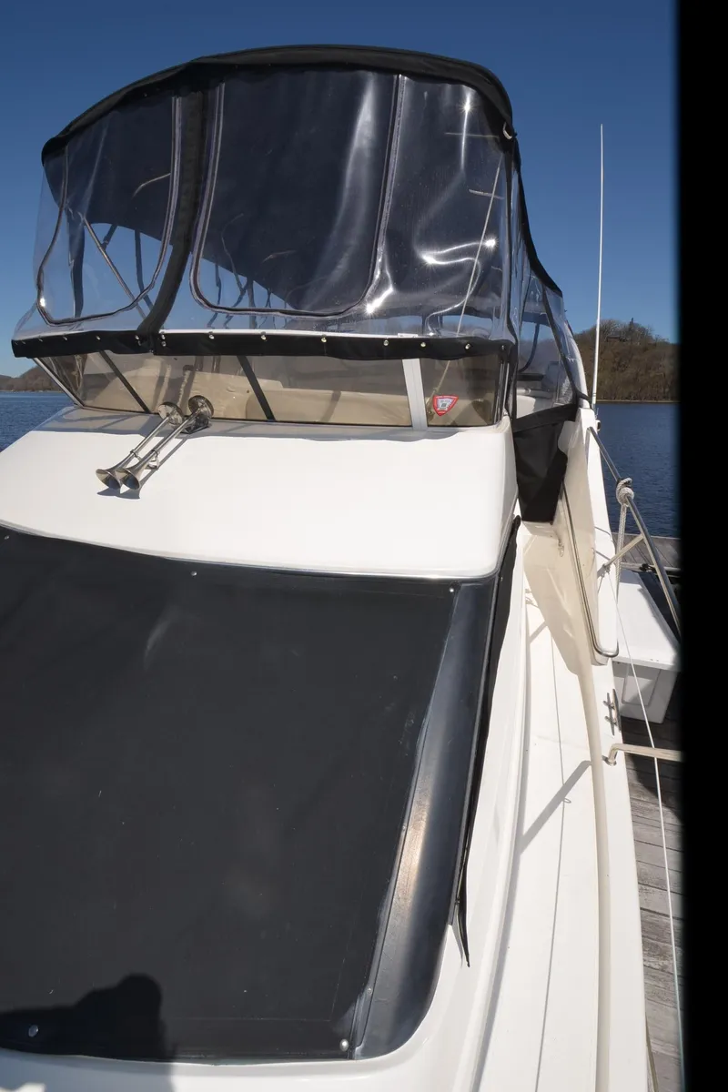 Slide: The Image of 2000 Silverton 330 Sport Bridge boat with clear canopy, docked on a sunny day. - 27