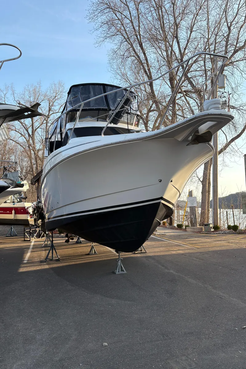 Slide: The Image of 2000 Silverton 330 Sport Bridge boat on stands, dockside, with trees in the background. - 30