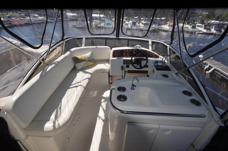 Slide: The Image of 2000 Silverton 330 Sport Bridge interior with seating and helm, docked at marina. - 5