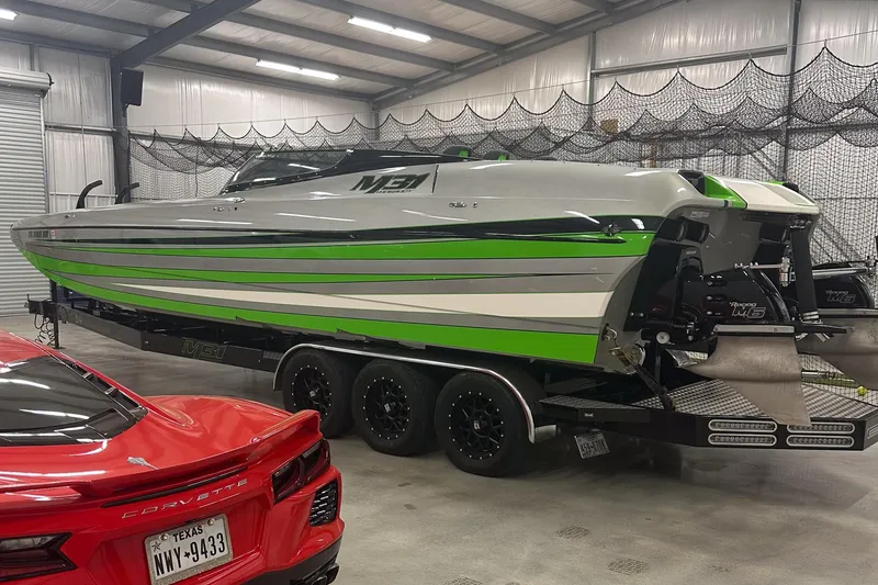 Slide: The Image of 2018 Daves Custom Boats M31 with green accents on trailer in garage. - 2
