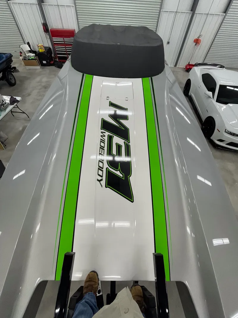 Slide: The Image of 2018 Daves Custom Boats M31 with green racing stripes in a garage. - 3