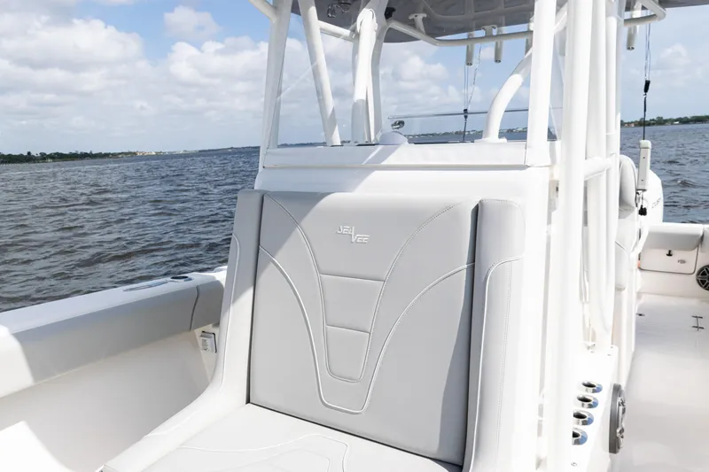 Slide: The Image of 2024 SeaVee 290B boat with sleek seating, cruising on a calm waterway under a partly cloudy sky. - 14
