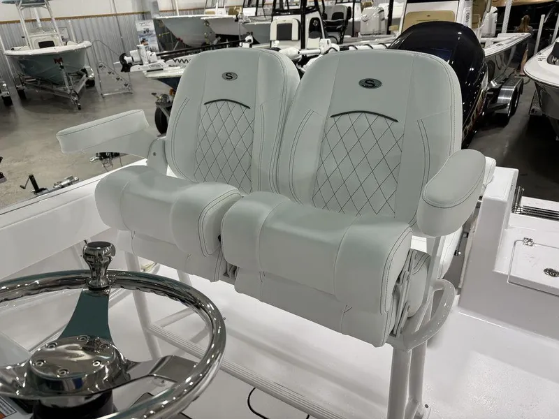 Slide: The Image of 2025 Sportsman Open 212 boat seats with diamond stitching and steering wheel in showroom. - 14