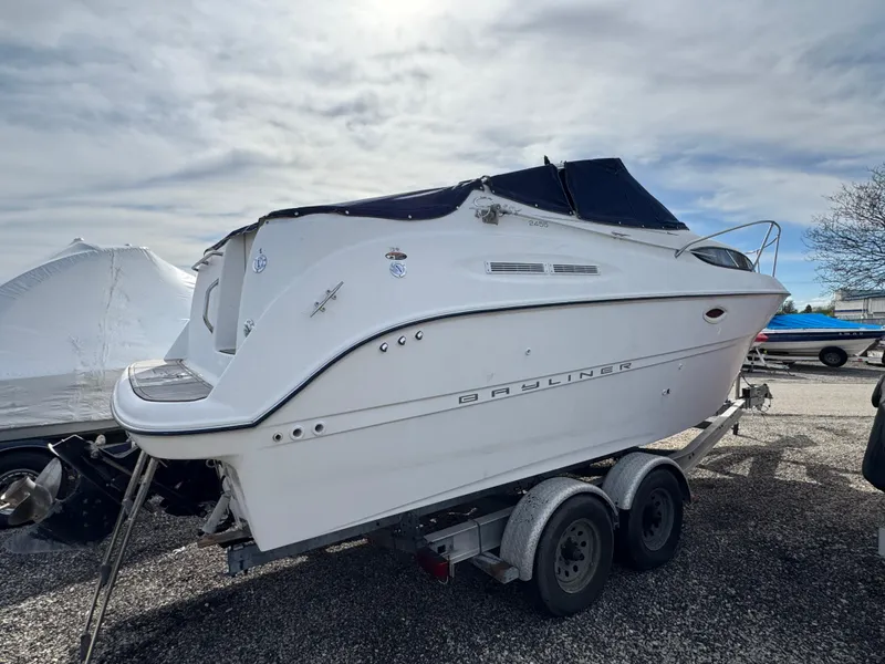 Slide: The Image of 2002 Bayliner 2455 Ciera boat on trailer, white exterior, parked outdoors under cloudy sky. - 11